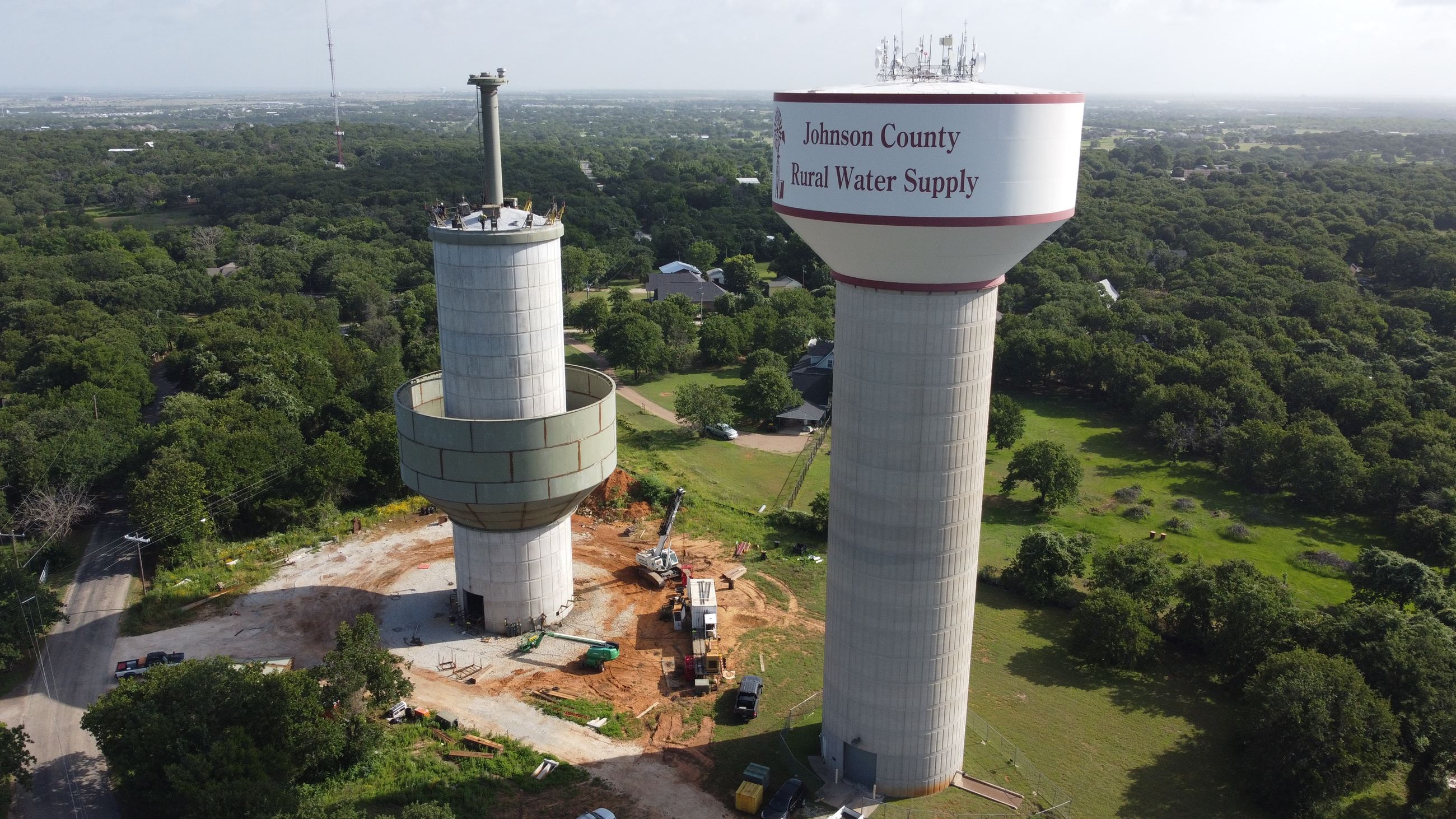 Image of two water towers, the one on the left has the bowl of the tank being raised up to the top.
